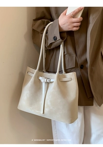 Detail of minimalist tote bag in cream faux leather with metal buckle and slim straps
