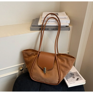 Close-up of brown suede bucket tote bag with gold metal clasp and slender shoulder strap