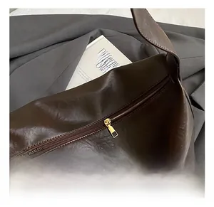 Détail de sac cabas vintage en cuir marron avec fermeture éclair dorée et finitions métalliques