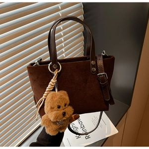 Dettaglio borsa a secchiello in camoscio marrone con manico in pelle e charm peluche