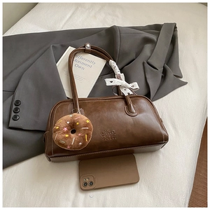 Détail d'un sac à main vintage marron avec pendentif en peluche et coutures contrastées