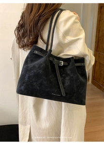 Detail of minimalist black matte suede tote bag with silver buckle and thin shoulder strap