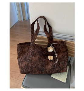 Close-up of leopard print tote bag with a cute brown teddy bear plush charm attached