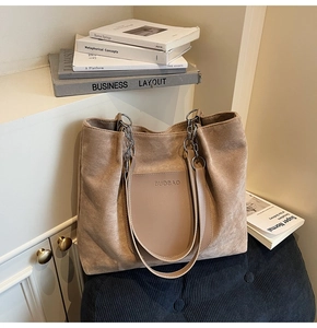 Detail view of brown faux suede tote bag featuring a leather pocket and metal chain strap