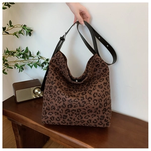 Detailed view of leopard print shoulder bag with adjustable wide strap on wooden bench