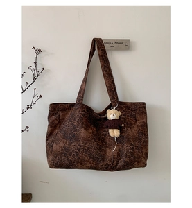 Detail of large leopard print tote bag with brown straps and cute teddy bear charm accessory