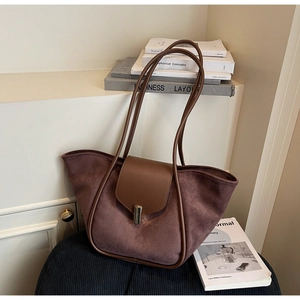 Detail of dark brown suede bucket tote bag with leather flap and metal clasp