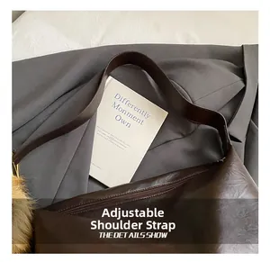 Détail de la bandoulière réglable et du pompon sur le sac fourre-tout en cuir marron
