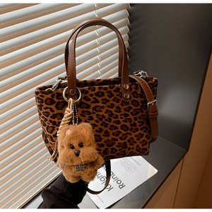 Dettaglio borsa tote leopardata con manici in pelle marrone e ciondolo a peluche