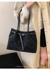 Detail of minimalist black suede tote bag featuring slim leather straps and metal buckle