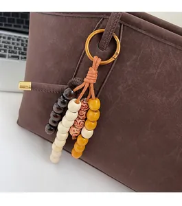 Detail of wooden beaded charm with orange cord on a brown leather tote bag