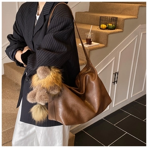 Gros plan d'un sac hobo marron texturé avec pendentif ours en peluche et fermeture éclair