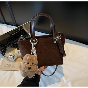 Dettaglio borsa a secchiello in camoscio marrone con ciondolo peluche Top Dog e PC