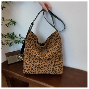 Close-up of leopard print canvas bag with adjustable black leather shoulder strap detail