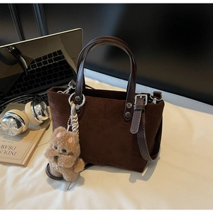 Dettaglio borsa tote in pelle scamosciata marrone con ciondolo a forma di cucciolo