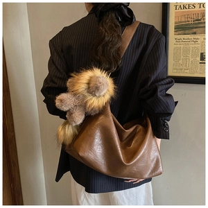 Gros plan d'un sac cabas vintage marron avec pendentif en fourrure sur mannequin