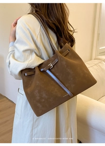 Close-up of minimalist dark brown suede tote bag featuring sleek buckle strap detail