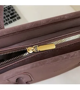 Close-up of high-quality smooth gold metal zipper on a brown leather tote handbag
