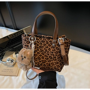 Borsa tote leopardata con manici in pelle marrone e ciondolo orsetto di peluche su tavolo