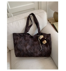 Detailed close-up of leopard print canvas tote bag with a cute brown teddy bear keychain
