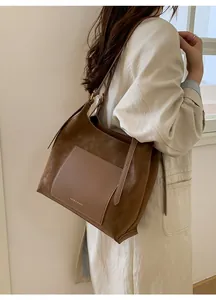 Detail of brown faux suede tote bag featuring a front pocket and gold hardware