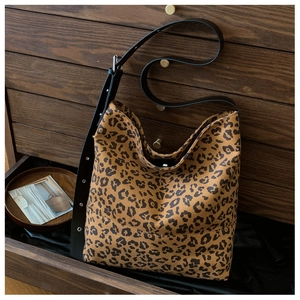 Detailed macro of leopard print hobo bag texture with adjustable wide strap and metal eyelets