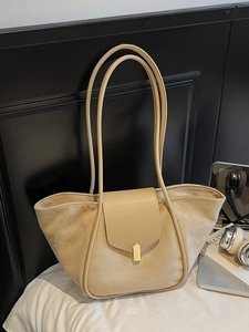 Minimalist beige suede tote bag with golden buckle and slender strap shown in studio set