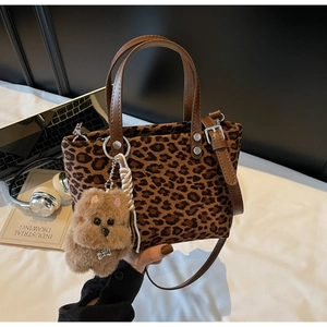 Dettaglio della borsa a secchiello leopardata con manici in pelle e ciondolo a cane