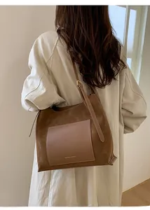 Detailed shot of brown suede tote bag featuring a leather front pocket and strap