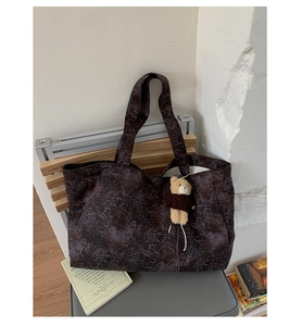 Detail of leopard print tote bag with plush bear charm on a minimalist chair