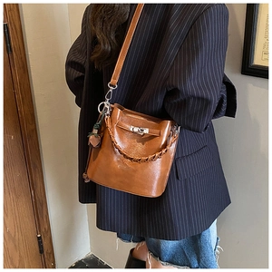 Detail view of brown vintage bucket bag with metal twist lock and braided handle strap