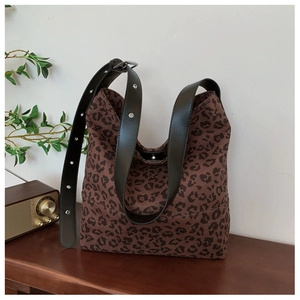 Detailed close-up of leopard print canvas fabric with black leather adjustable strap