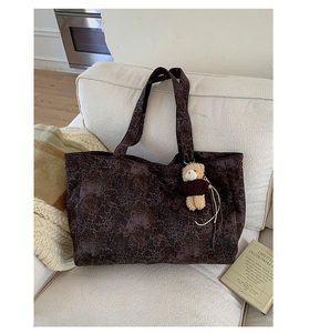 Large leopard print tote bag with plush bear charm on a cozy beige sofa setting