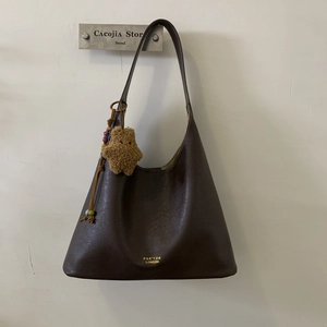Detail view of dark brown leather underarm bag with gold logo and plush star charm