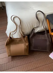 Close-up of camel and dark brown suede tote bags with leather pockets and brand logo