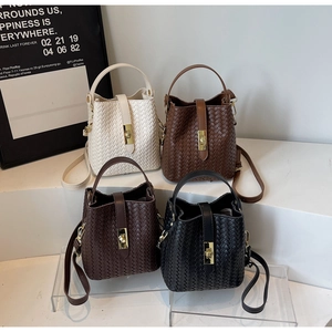 Detail view of woven bucket bags in four colors with gold twist locks on display