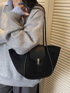 Minimalist black tote bag in matte leather featuring a stylish golden metal clasp