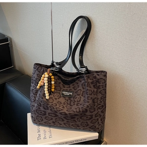 Detail of leopard print tote bag with leather straps and decorative wooden bead tassel