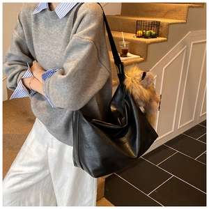 Détail d'un grand sac hobo noir avec pendentif peluche porté par un mannequin femme