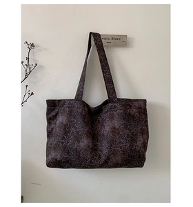 Detail of dark leopard print tote bag hanging on minimalist metal rack in a shop