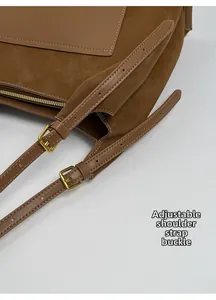Detail of adjustable shoulder strap with gold metal buckle on brown suede tote bag