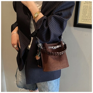 Detail of dark brown bucket bag featuring woven handle and silver metal lock closure