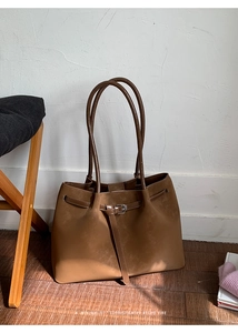 Close-up of brown suede tote bag featuring a decorative belt buckle and retro design