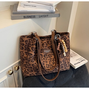 Detail of leopard print tote bag with leather handles and colorful beaded charm