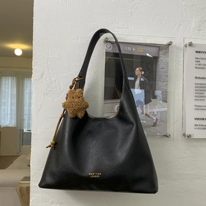 Detailed shot of black leather hobo shoulder bag with a cute brown plush bear charm