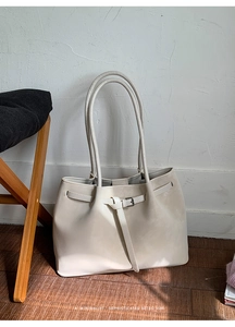 Detailed view of cream leather tote bag with elegant buckle strap and minimalist retro design