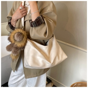 Gros plan du sac hobo beige en cuir plissé avec un charmant porte-clé lion en peluche