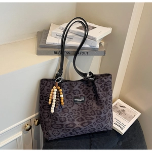 Close-up of leopard print tote bag with black leather straps and wooden bead charm