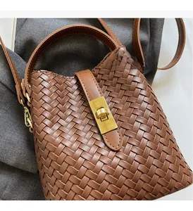 Detail of brown woven leather bucket bag with luxury gold twist-lock and fine texture