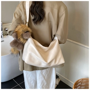 Détail du grand sac bandoulière blanc crème avec un porte-clés singe en peluche mignon